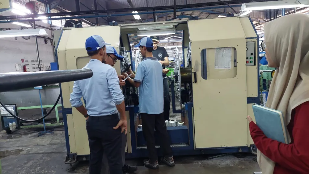 Tim produksi memeriksa mesin pemintal benang di lantai pabrik
